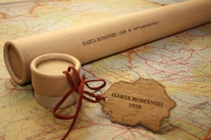 Harta României Mari, accesorizată cu baghete de lemn de marupa, are ca suport de protecție un tub de carton bordurat, personalizat prin gravare, cu capac, de care este legată o eticheta de lemn cu forma României Mari, gravată.